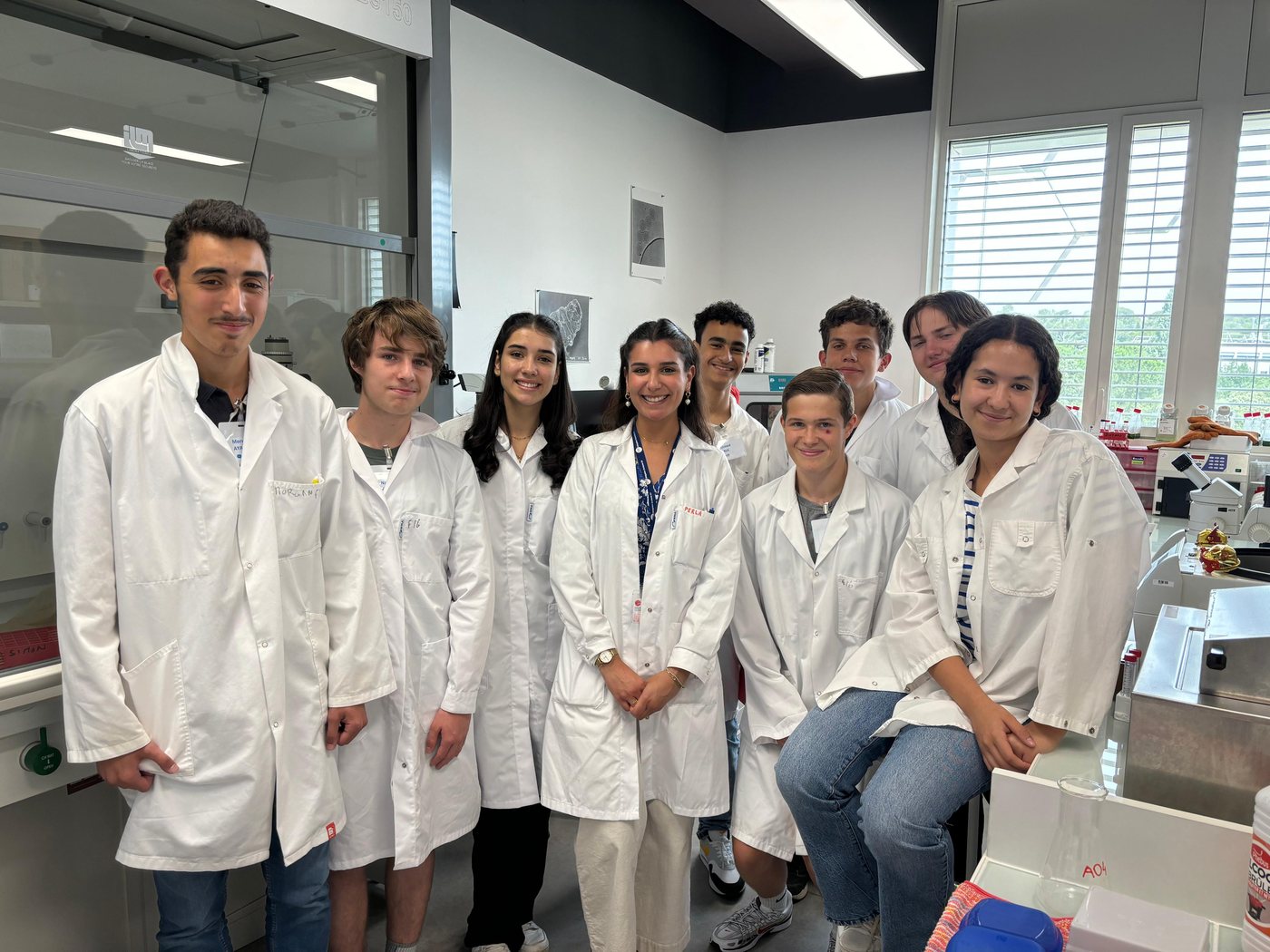 Perla Makhoul in a lab coat with a group of school students in a teaching laboratory at the IBMM